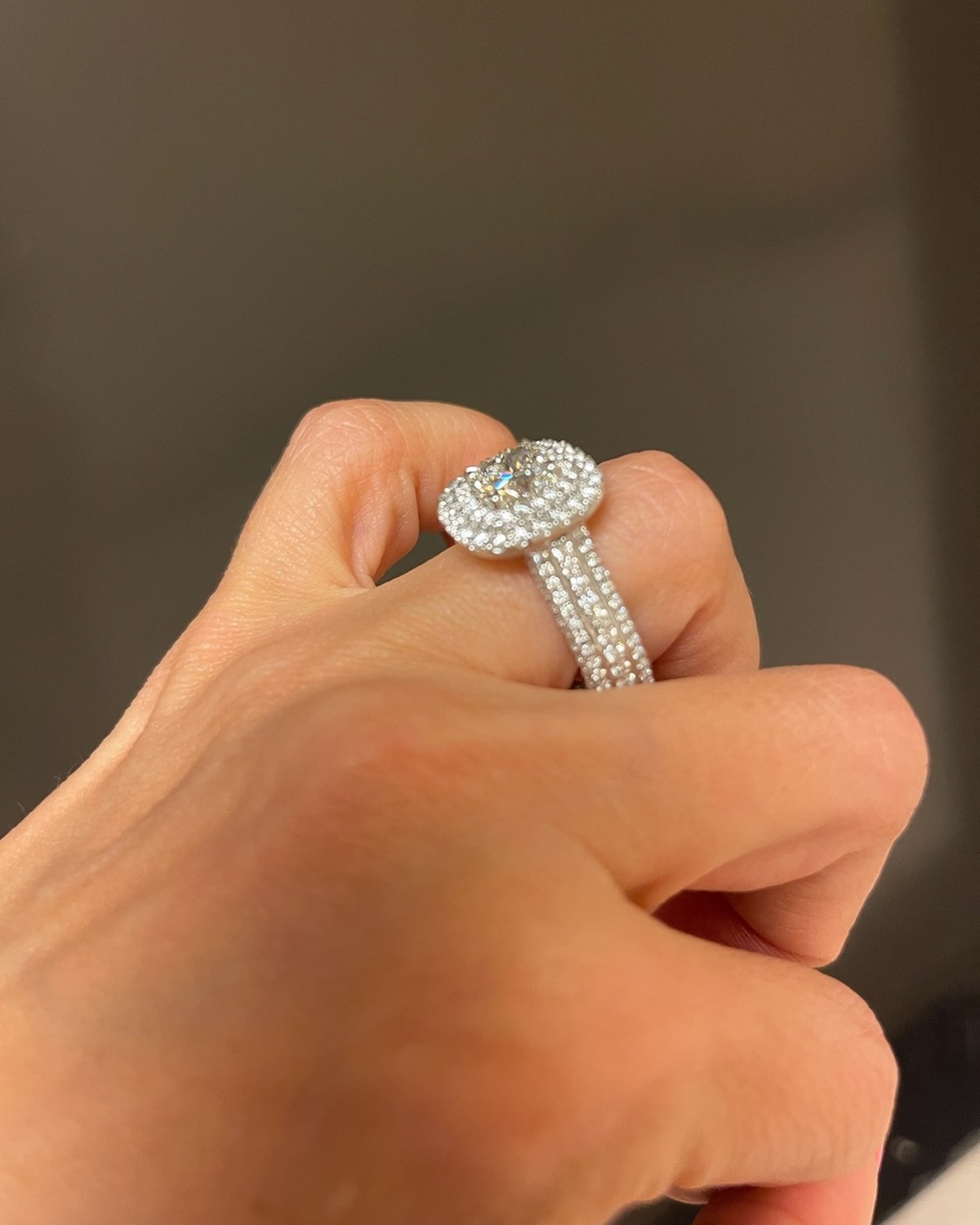 Cushion double-halo ring photographed on a closed hand, showing the scale of the halo