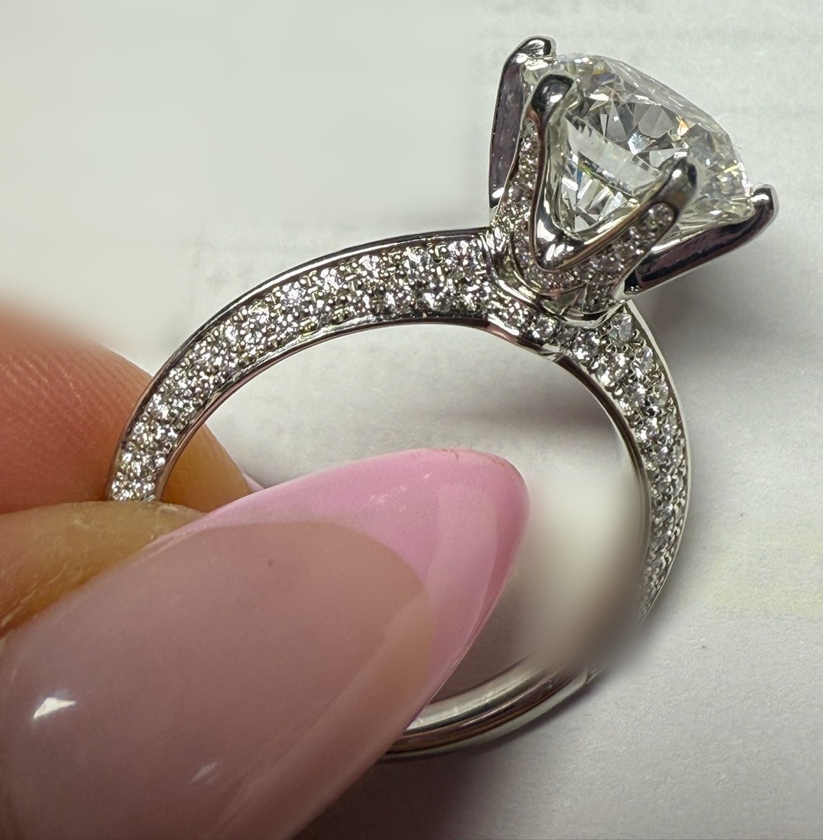 Profile macro of a round diamond solitaire in a cathedral setting with a hidden halo and a three-row micropavé shank