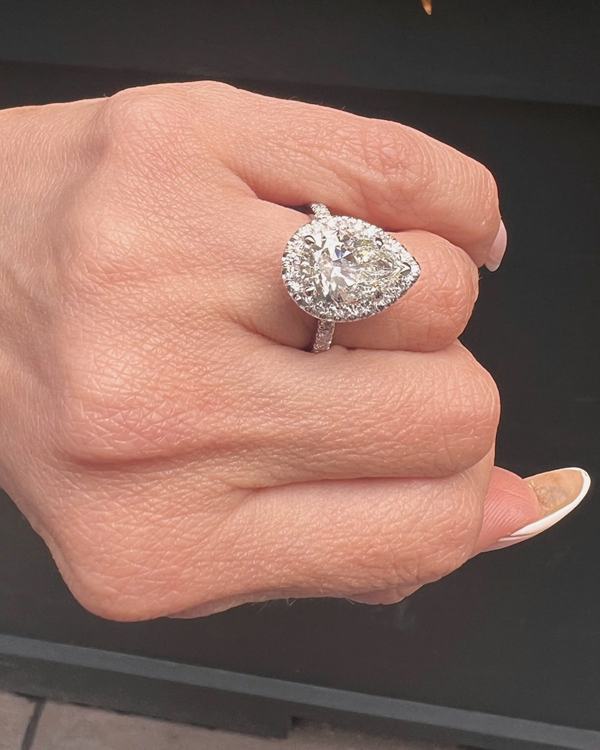 Pear-shape halo ring photographed from above on a closed hand in daylight