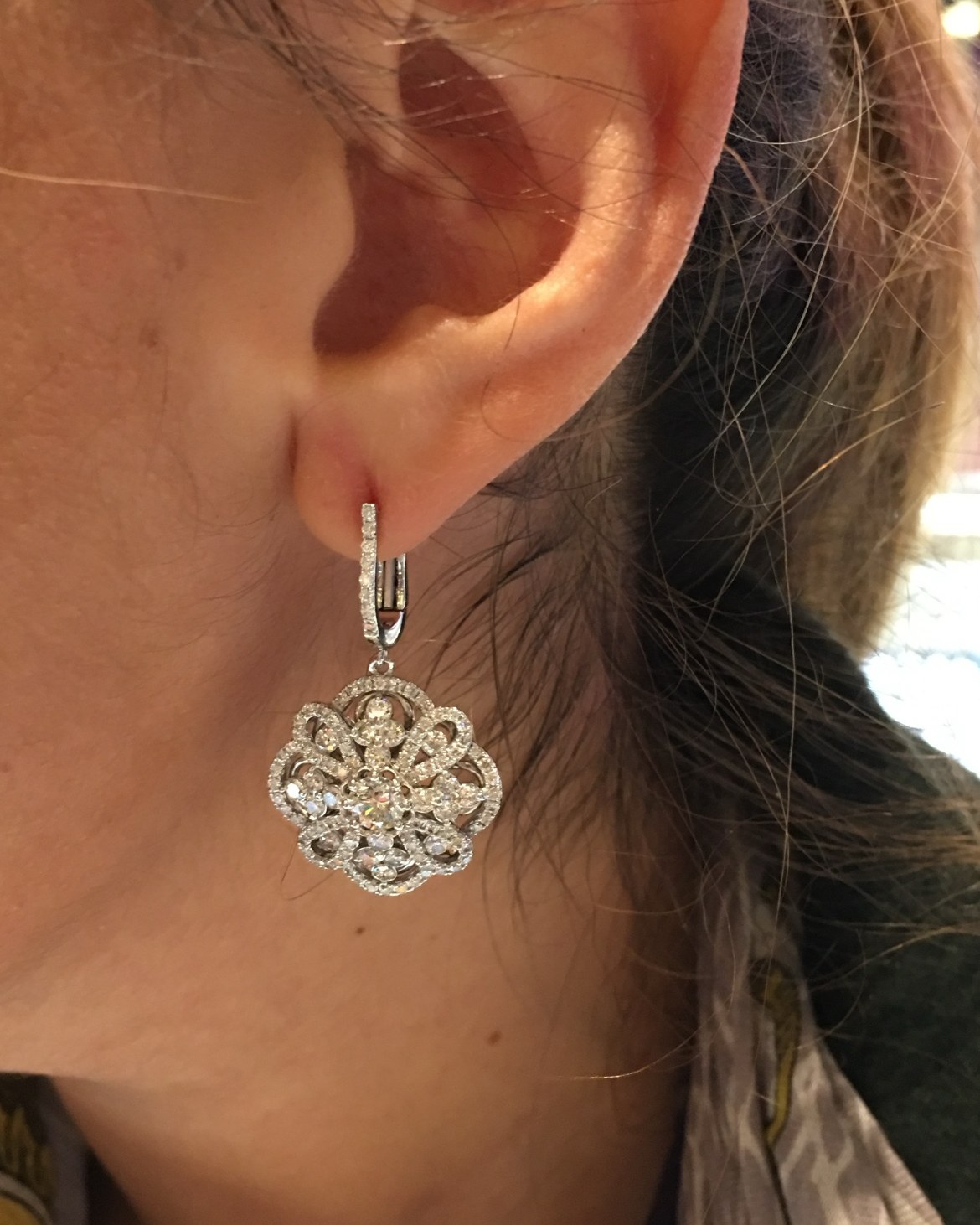 Rose gold openwork floral diamond drop earring worn at the ear, seen in profile