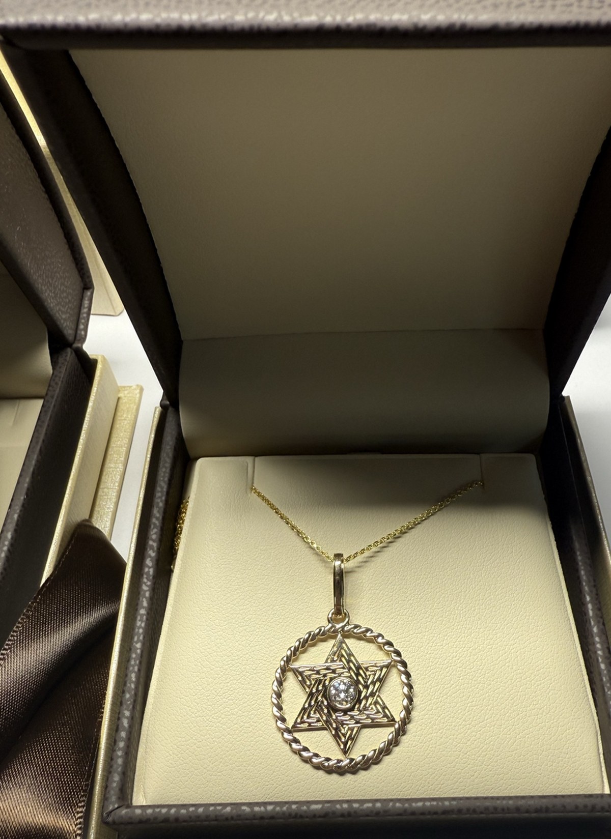 Yellow gold Star of David inside a twisted rope circle with a bezel-set diamond center, in its presentation box